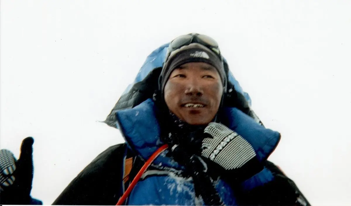 Kami Rita Sherpa standing on the summit of Mount Everest.