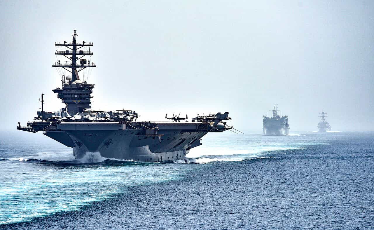 USS Dwight D. Eisenhower aircraft carrier transits the Strait of Hormuz escorted by warships.
