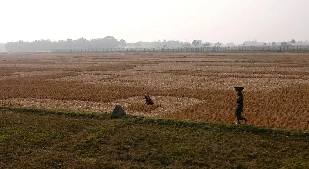 Border fence between India and Bangladesh near Hili, with a boundary stone in the foreground.